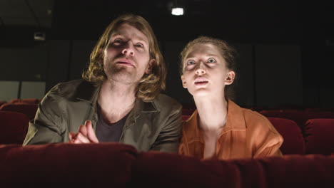 Front-View-Of-Concentrated-Couple-Sitting-In-The-Cinema-While-They-Watching-A-Movie