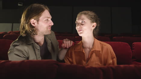 Front-View-Of-Couple-Sitting-In-The-Cinema-While-They-Talking-And-Looking-At-Camera