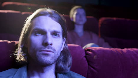 Close-Up-View-Of-Blond-Man-Watching-A-Movie-In-The-Cinema-With-The-Lights-Off