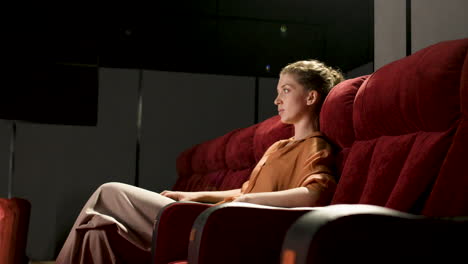 Side-View-Of-Blonde-Woman-Sitting-In-The-Cinema-And-Watching-A-Movie