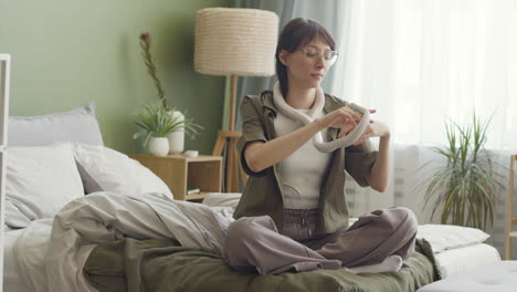 Young-Woman-Holding-Her-White-Pet-Snake-While-Sitting-On-Bed-At-Home