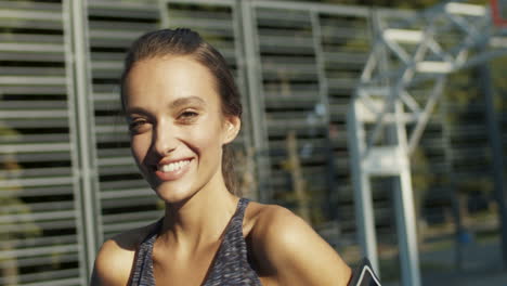 Close-Up-Of-A-Sporty-Woman-Smiling-Cheerfully-At-The-Camera-While-Standing-At-Sport-Court-On-A-Summer-Day