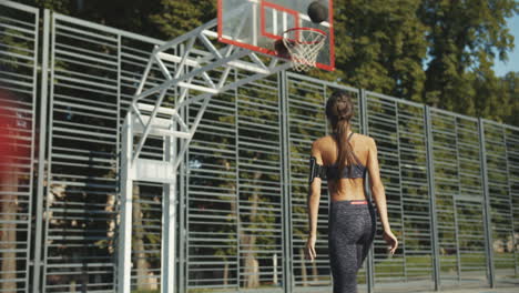 Rückansicht-Einer-Sportlichen-Frau,-Die-Ball-Schießt-Und-Auf-Dem-Basketballplatz-Im-Freien-Punktet