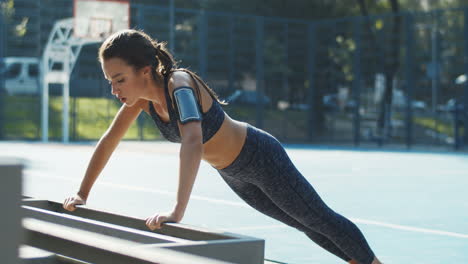 Sporty-Girl-Doing-Push-Ups-From-Bench-At-Outdoor-Basketball-Court-In-Summer-Morning