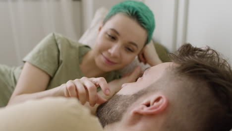 Loving-Woman-Touching-Her-Boyfriend's-Face-While-Relaxing-On-The-Bed-And-Looking-At-Each-Other