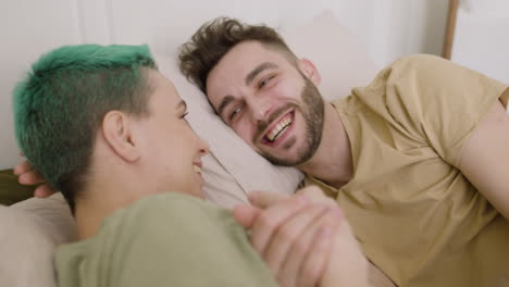 Happy-Young-Couple-Talking-And-Laughing-Together-While-Lying-On-The-Bed