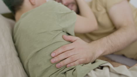 Close-Up-Of-The-Hand-Of-A-Man-Hugging-His-Girlfriend-On-The-Bed