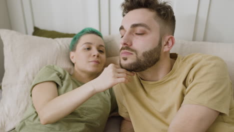 Loving-Woman-Touching-Her-Boyfriend's-Face-While-Relaxing-On-The-Bed-At-Home