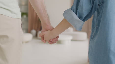 Back-View-Of-An-Unrecognizable-Couple-Standing-And-Holding-Hands-At-Home