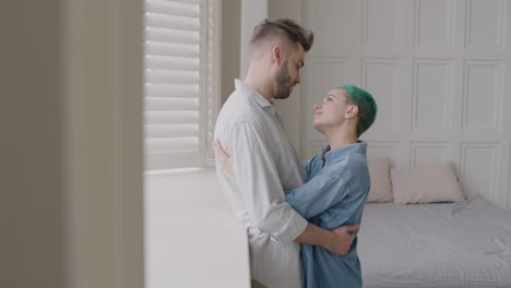 Loving-Couple-Tenderly-Looking-At-Each-Other-And-Hugging-While-Standing-Next-To-The-Window-In-The-Bedroom