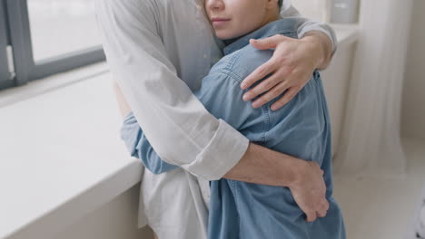 Young-Woman-With-Closed-Eyes-Hugging-Her-Boyfriend-At-Home