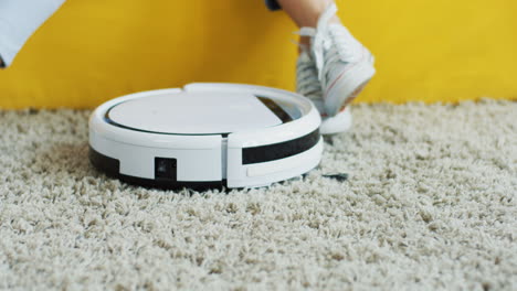Close-Up-Of-The-Mini-Vacuum-Cleaner-On-The-Floor-And-Female-And-Kids-Feet-On-The-Background