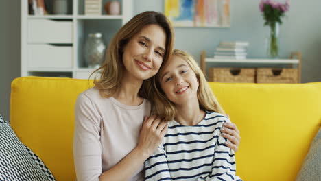Portrait-Of-Mother-And-Daughter-Sitting-On-Yellow-Couch-1