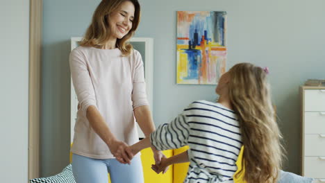 Happy-Relaxed-Mother-And-Little-Daughter-Holding-Their-Hands-And-Dancing-In-The-Living-Room