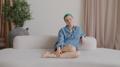 Young-Woman-With-Blue-Hair-And-Wearing-A-Denim-Shirt-Sitting-On-A-Big-Sofa-Looking-At-Camera