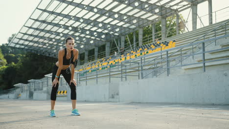 Young-Jogger-Woman-Training-In-The-Stadium,-Then-Stops-And-Keeps-On-Jogging-On-A-Summer-Sunny-Morning