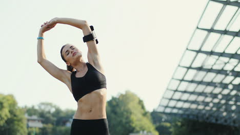 Young-Jogger-Woman-Doing-Exercises-And-Stretching-Hands-In-The-Stadium-On-A-Summer-Day