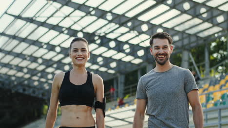 Young-Jogger-Couple-Giving-Five-To-Each-Other-And-Smiling-To-The-Camera-After-Running-Training-Time