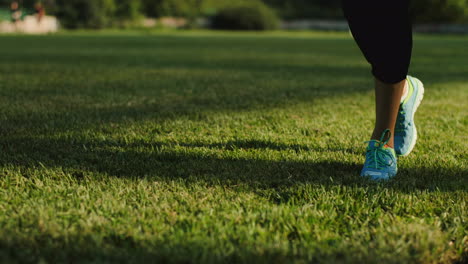 Close-Up-View-Of-Jogger-Woman-Feet-In-Trainers-Jogging-On-The-Green-Grass-Outdoor