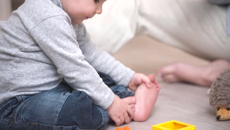 Nahaufnahme-Eines-Babys,-Das-Auf-Dem-Boden-Sitzt-Und-Mit-Bauklötzen-Spielt,-Und-Seine-Mutter-Hält-Seine-Hände