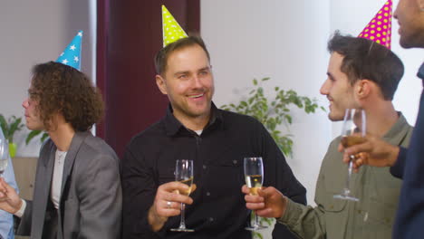 Happy-Multiethnic-Group-Of-Male-Colleagues-Holding-Champagne-Glass-And-Talking-Together-During-A-Party-At-The-Office