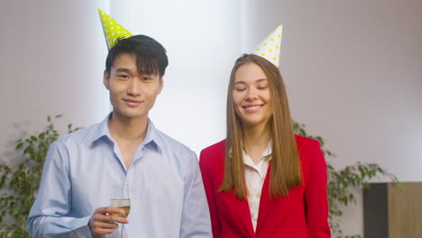 Portrait-Of-An-Young-Man-With-Champagne-Glass-And-A-Girl-Smiling-And-Looking-At-Camera-At-The-Office-Party