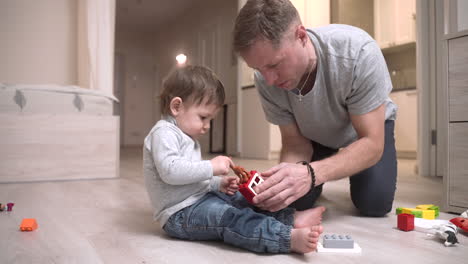 Baby-Und-Vater-Sitzen-Im-Wohnzimmer-Auf-Dem-Boden-Und-Spielen-Mit-Spielzeug