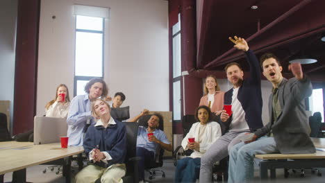 Group-Of-Multiethnic-Colleagues-Watching-A-Sportive-Match,-Cheering-And-Supporting-Their-Team-At-The-Office