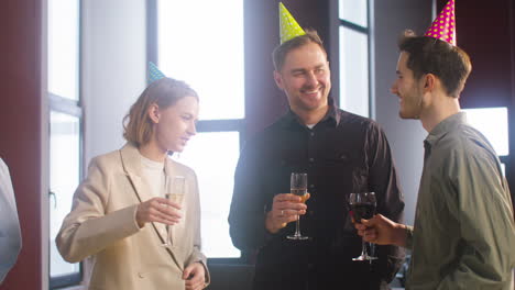 Happy-Colleagues-Holding-Drinks-And-Talking-Together-At-The-Office-Party