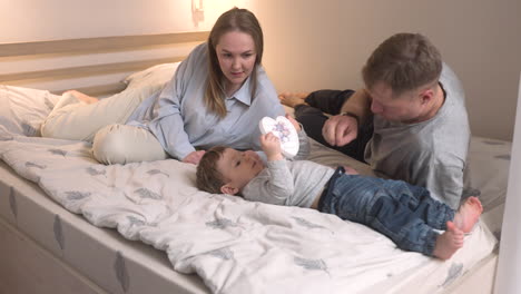 Parents-Playing-With-His-Son-On-The-Bed-While-The-Baby-Is-Holding-A-Toy-Heart