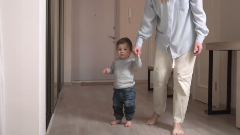 Mother-Helps-Her-Baby-To-Get-Up-From-The-Floor-And-Take-His-First-Steps-At-Home