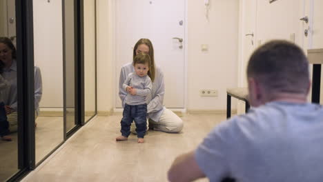 Mother-And-Her-Baby-At-One-End-Of-The-Corridor-At-Home-While-The-Father-Encouraging-The-Baby-To-Walk-To-The-Other-End