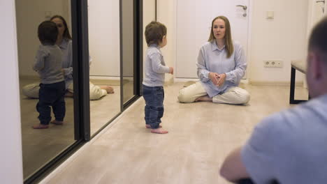 Mother-And-Her-Baby-At-One-End-Of-The-Corridor-At-Home-While-The-Father-Encouraging-The-Baby-To-Walk-To-The-Other-End-1