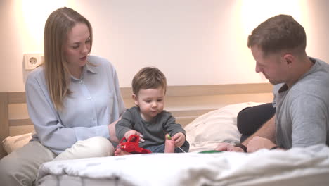 Distant-View-Of-A-Baby-Playing-With-Toy-On-The-Bed-With-His-Parents