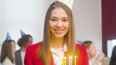 Portrait-Of-A-Beautiful-Woman-Holding-A-Birthday-Cake-And-Looking-At-Camera-During-A-Party-In-The-Office-1