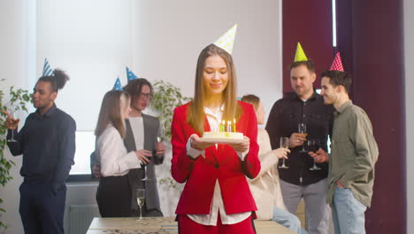 Portrait-Of-A-Beautiful-Woman-Holding-A-Birthday-Cake-And-Looking-At-Camera-During-A-Party-In-The-Office-2