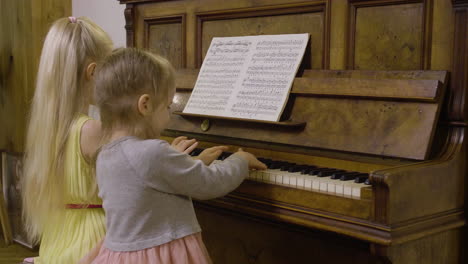 Side-View-Of-Two-Little-Girls-Playing-Old-Piano-At-Home-1