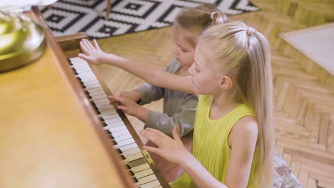 Two-Little-Girls-Playing-Old-Piano-At-Home