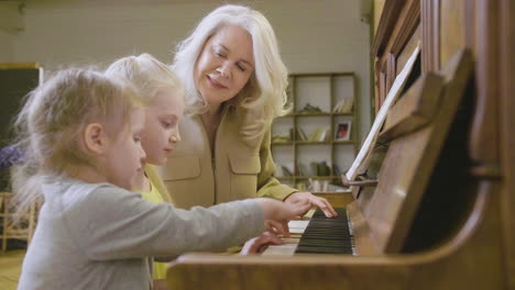 Two-Little-Girls-Playing-Old-Piano-At-Home-While-Their-Grandmother-Watching-Them-1