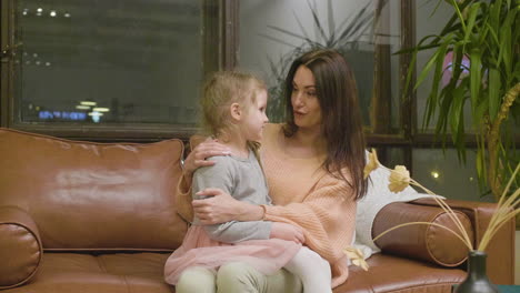 Happy-Mother-Sitting-On-Sofa-With-Her-Little-Daughter-And-Talking-With-Her