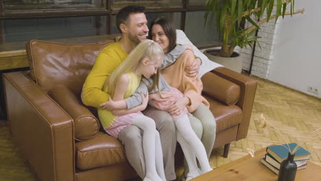 Zoom-Out-Of-A-Happy-Family-Hugging-And-Spending-Time-Together-While-Sitting-On-Sofa-At-Home