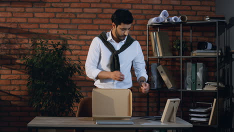 Stylish-Arabian-Businessman-Packing-A-Box-With-Office-Stuff-From-His-Table-And-Leaving-The-Office-With-This-Box-In-Hands-As-Been-Fired
