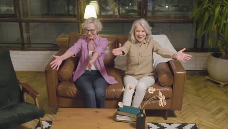 Two-Little-Girls-Running-And-Hugging-Their-Happy-Grandmothers-Who-Sitting-On-Sofa-In-The-Living-Room-At-Home-2