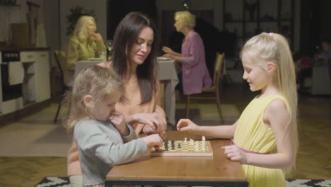 Mother-And-Her-Two-Little-Daughters-Playing-Chess-At-Home-1