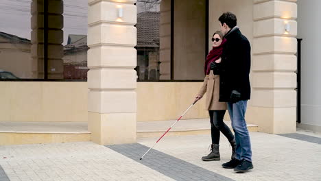 Side-View-Of-A-Man-And-A-Blind-Woman-Walking-In-The-Street