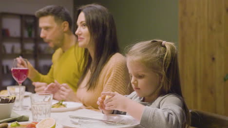 Little-Blonde-Girl-Sitting-Near-Her-Parents-At-A-Family-Dinner
