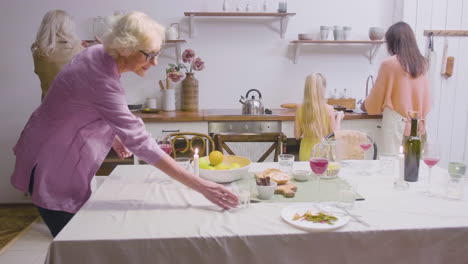 Mother,-Daughter-And-Grandmothers-Removing-The-Plates-From-The-Table-After-Family-Dinner