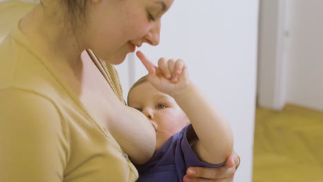 Close-Up-Of-A-Loving-Young-Mother-Breastfeeding-And-Playing-With-Her-Baby-Boy-At-Home
