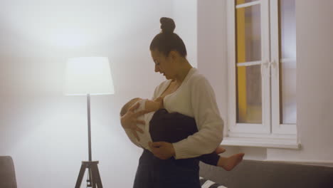 Young-Mother-Breastfeeding-And-Cuddling-Her-Baby-Boy-While-Standing-In-The-Living-Room-At-Home