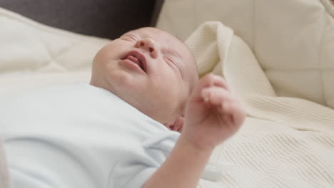 Close-Up-Of-A-Cute-Newborn-Baby-Lying-On-Bed-And-Crying